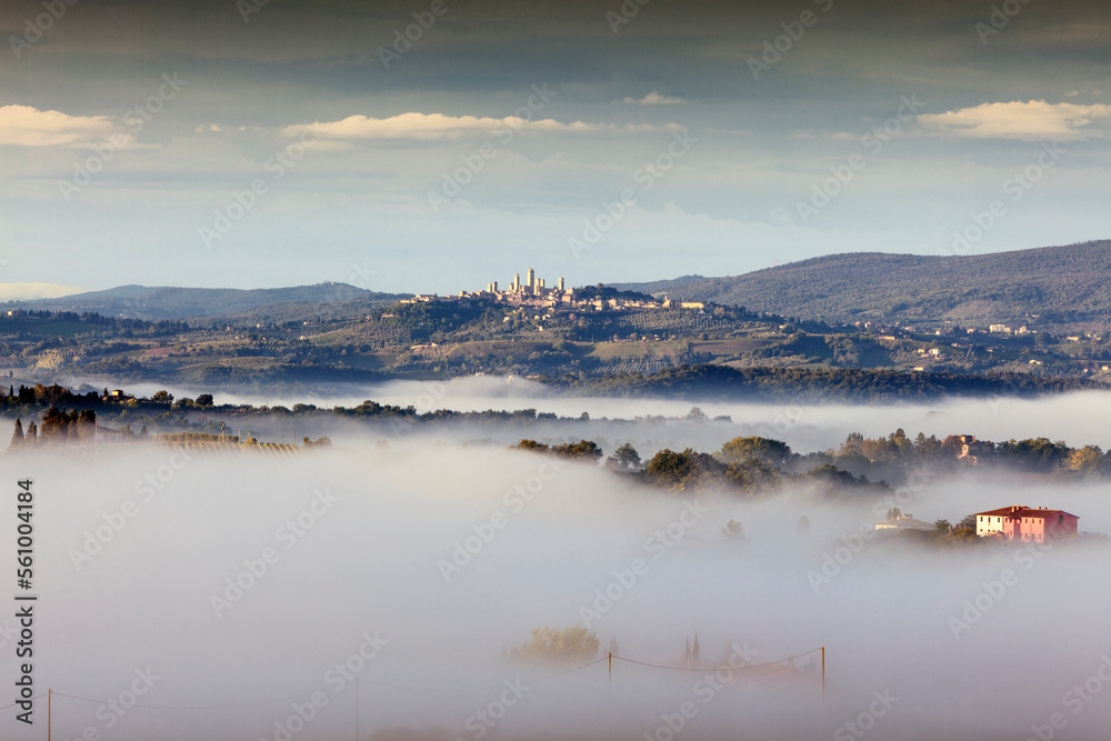 San Gimignano, Siena. Panorama del borgo con le torri in collina e le valli nella nebbia del mattino