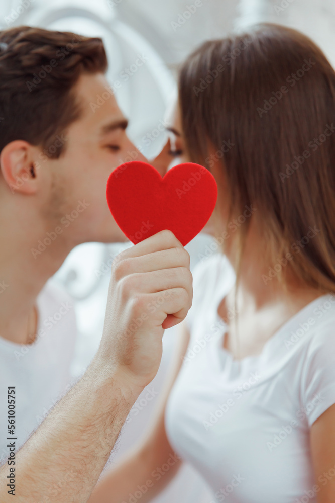 Two young people kissing behind a paper heart. Celebrating Saint Valentine's day. Two young people kissing behind a paper heart. Celebrating Saint Valentine's day.