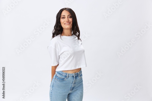 Woman in white t-shirt on white background brunette hands up gestures and signals poses in jeans emotion, lifestyle smiles, copy space