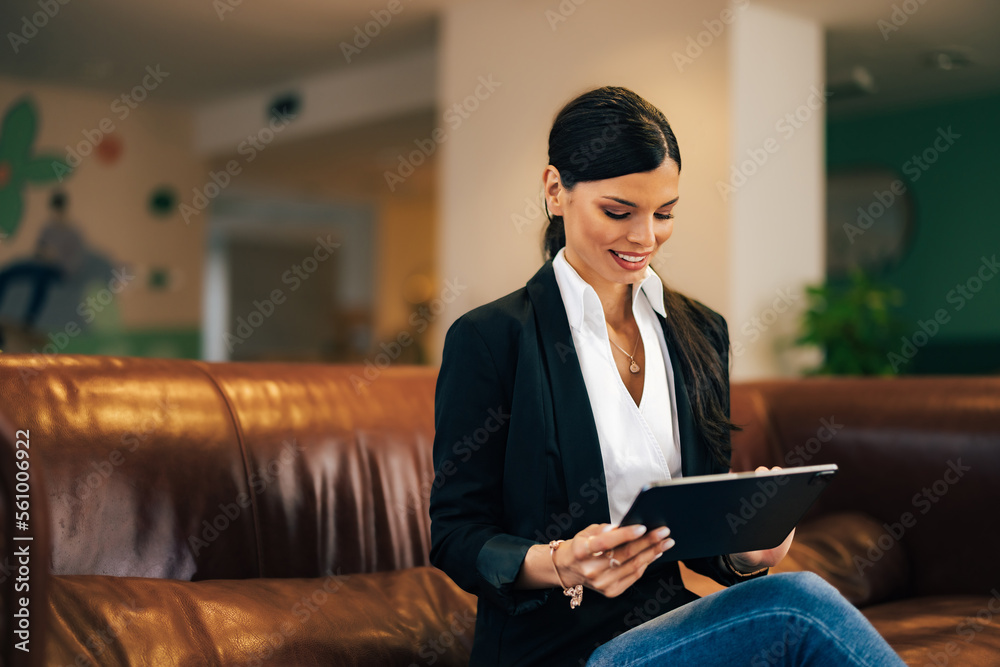 Smiling female employee having an online meeting over the digital tablet, sitting at the workplace. Smiling female employee having an online meeting over the digital tablet, sitting at the workplace.