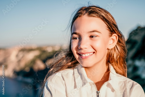 Adorable teenage girl outdoors enjoying sunset at beach on summer day. Close up portrait of smiling young romantic teenager girl with long hair on beach at summer evening. Travel and holidays