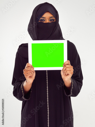 Muslim woman, tablet and green screen for marketing, advertising or mockup against a grey studio background. Portrait of woman in hijab holding touchscreen with green chromakey screen or display