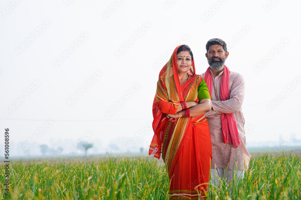 Indian farmer couple standing together at agriculture field.