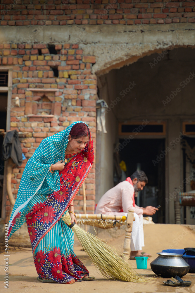 Indian rural woman sweeping in front of home.
