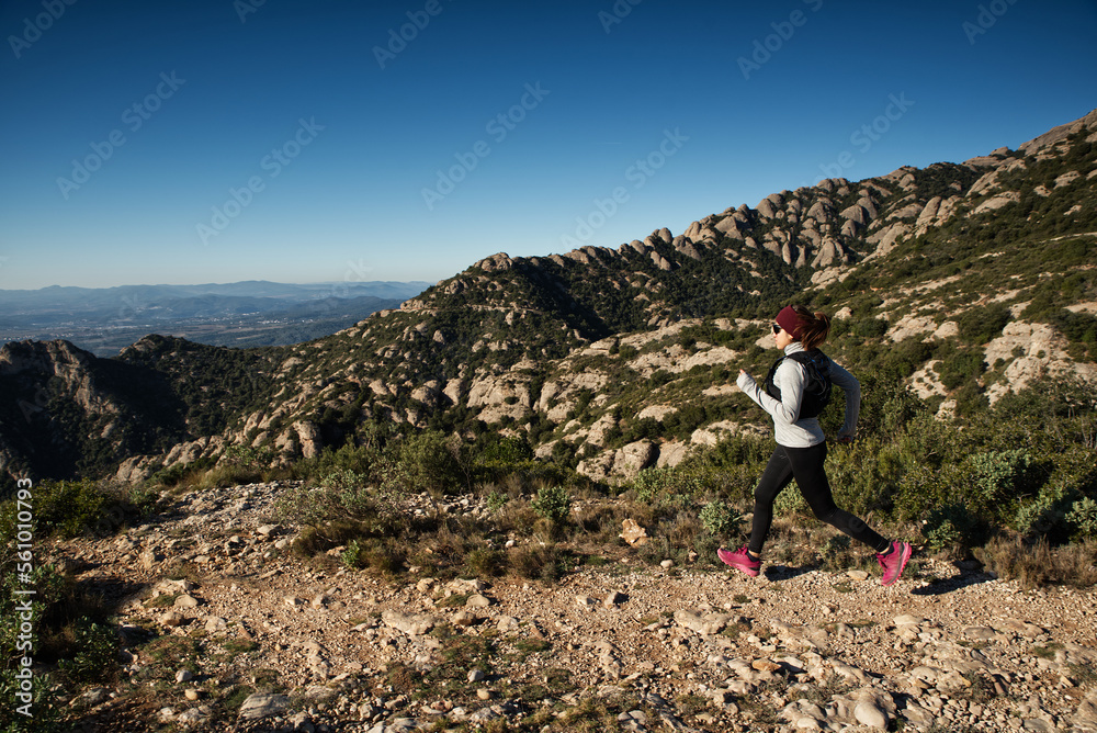 Athlete woman, runs to the top of a mountain where there is a cross, in Catalonia, Spain.