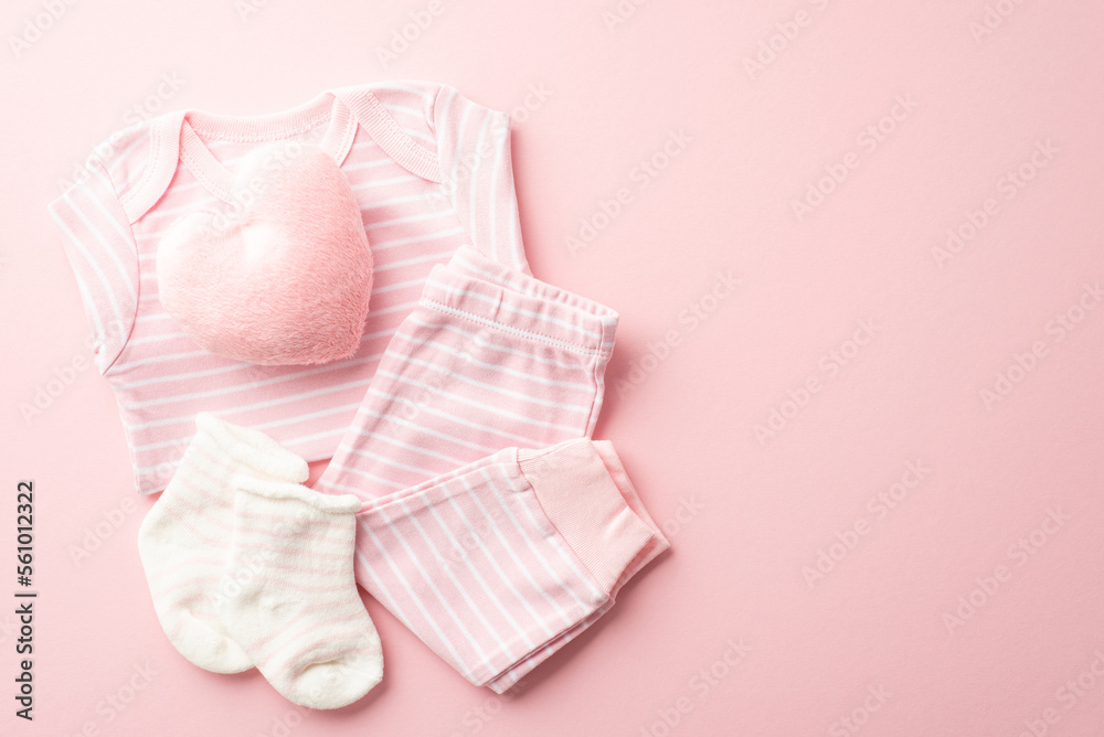 Baby shower concept. Top view photo of pink infant clothes shirt pants socks and heart shaped fluffy toy on isolated pastel pink background with blank space