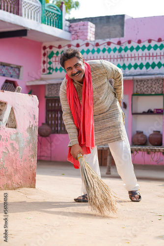 Indian farmer sweeping with a broom at home photo