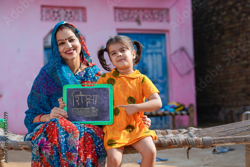 education concept : Indian rural woman showing shiksha words in hindi calligraphy with daughter photo