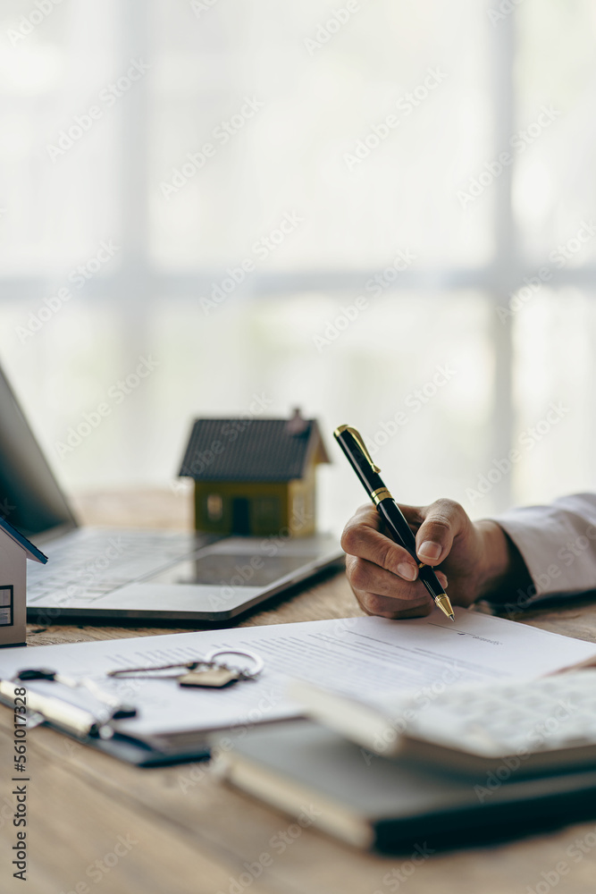 Fototapeta premium Real estate office, home sales agent sitting at desk with contract documents and house plans next to sale and rental concept.