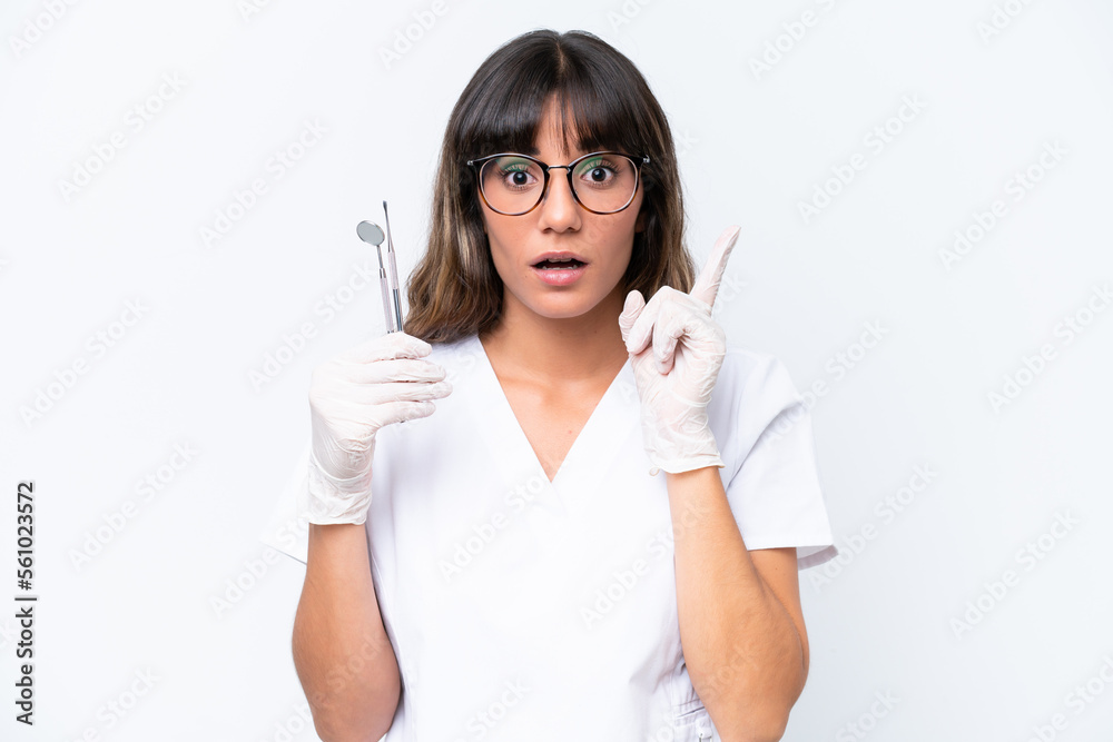 Dentist caucasian woman holding tools isolated on white background intending to realizes the solution while lifting a finger up Dentist caucasian woman holding tools isolated on white background intending to realizes the solution while lifting a finger up
