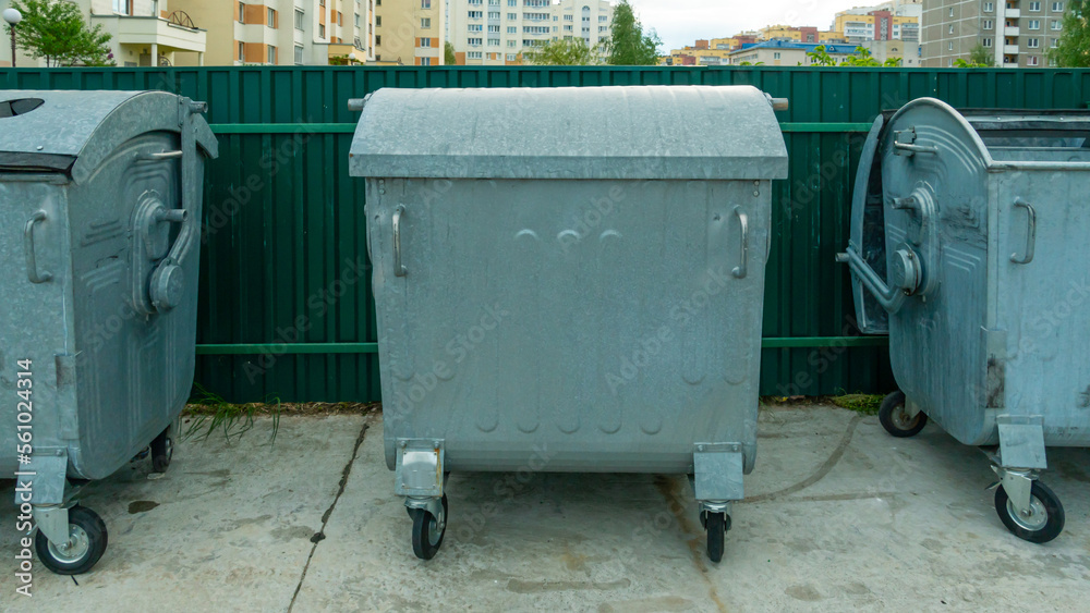 Modern metal containers for separate garbage collection. Garbage cans in the city on the background of a house. Environmental disaster, problems of waste removal, collection and disposal in a big city Modern metal containers for separate garbage collection. Garbage cans in the city on the background of a house. Environmental disaster, problems of waste removal, collection and disposal in a big city