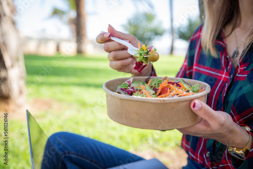 Close up of a salad being eaten by a girl sitting in a public park, vegan food, healthy lifestyle.