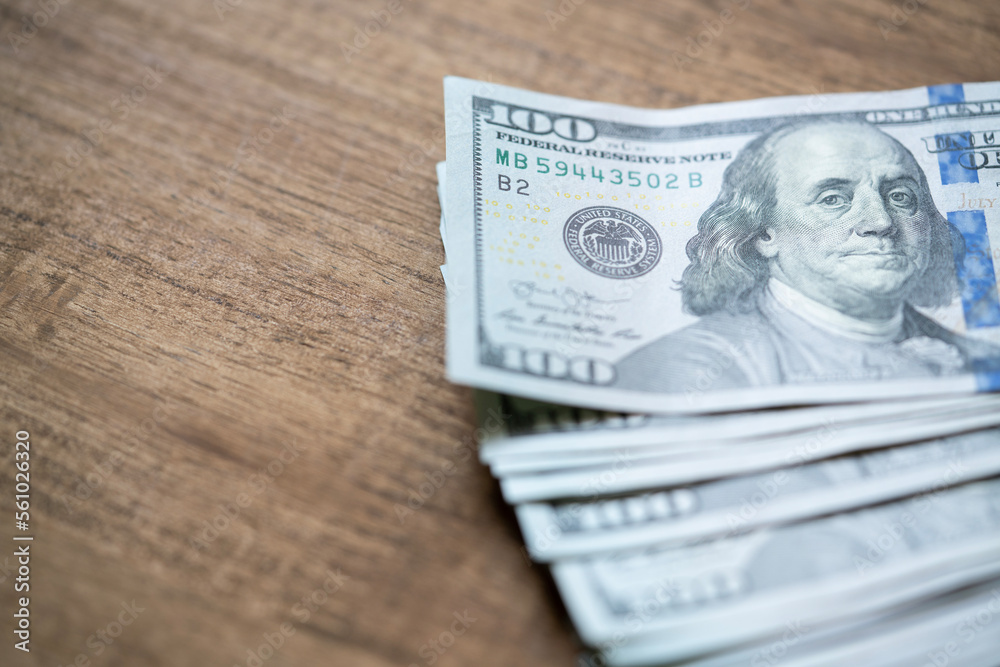 US one hundred dollars bills money on the wooden table, finance and business concept US one hundred dollars bills money on the wooden table, finance and business concept