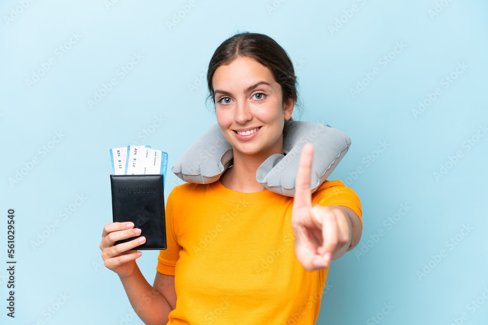 Young beautiful woman with Inflatable travel Pillow isolated on blue background showing and lifting a finger Young beautiful woman with Inflatable travel Pillow isolated on blue background showing and lifting a finger