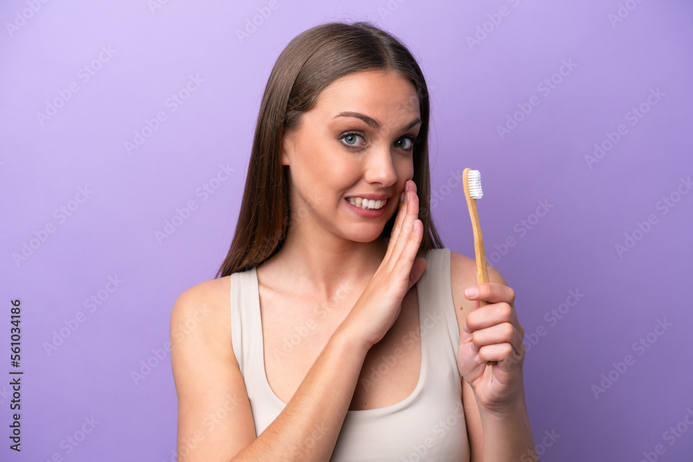 Young caucasian woman brushing teeth isolated on purple background whispering something Young caucasian woman brushing teeth isolated on purple background whispering something