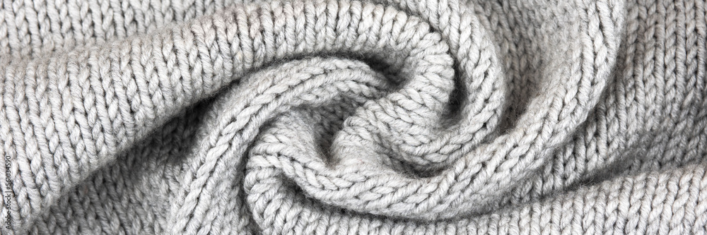 Knitted gray background. Close-up of a knitted blanket. Wavy folds material. Knitted warm grey sweater or scarf. Banner, copy space Knitted gray background. Close-up of a knitted blanket. Wavy folds material. Knitted warm grey sweater or scarf. Banner, copy space