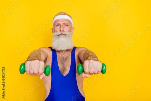 Photo of cool handsome man pensioner dressed blue overall pumping hands muscles empty space isolated yellow color background