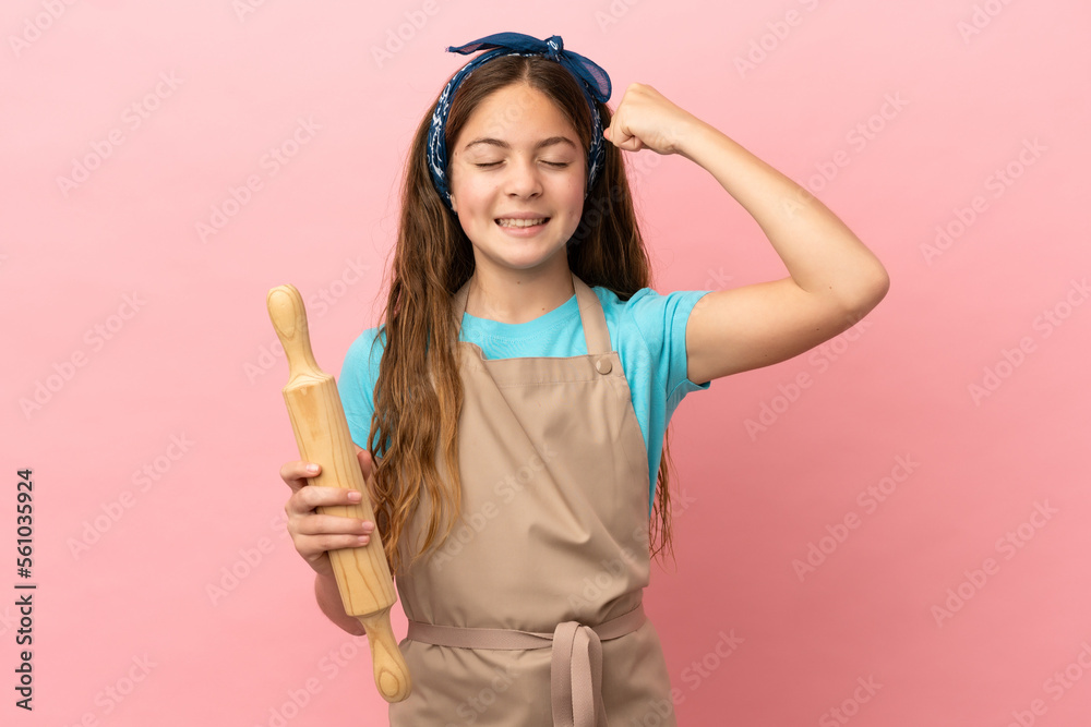 Little caucasian girl holding a rolling pin isolated on pink background doing strong gesture Little caucasian girl holding a rolling pin isolated on pink background doing strong gesture