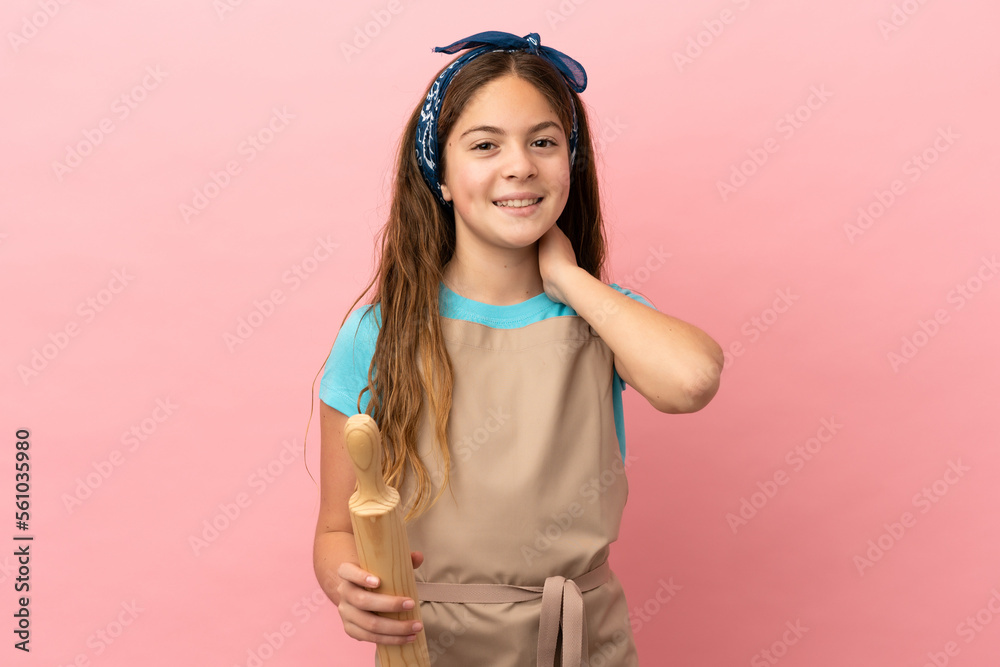 Little caucasian girl holding a rolling pin isolated on pink background laughing Little caucasian girl holding a rolling pin isolated on pink background laughing
