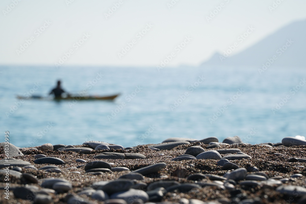 Sea stones on the shore against the background of a kayak