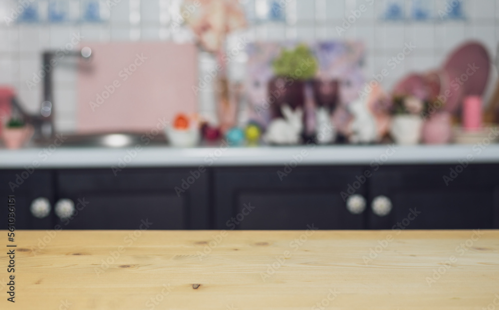 Wooden empty table on the background of the kitchen with Easter eggs, hares