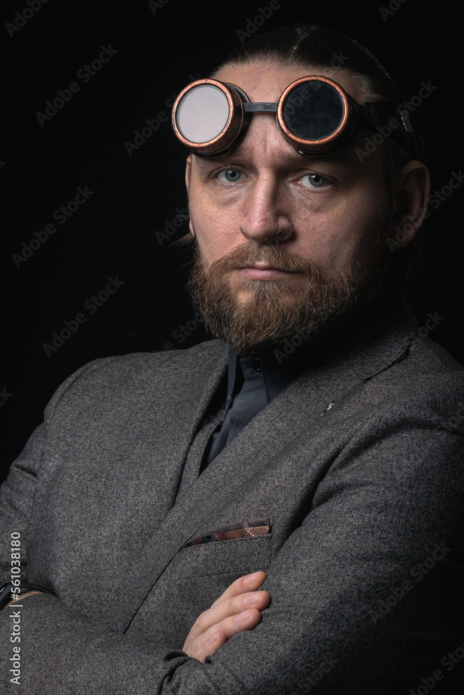 Fototapeta premium charismatic man in a classic suit and steampunk goggles on a black background stylish Portrait