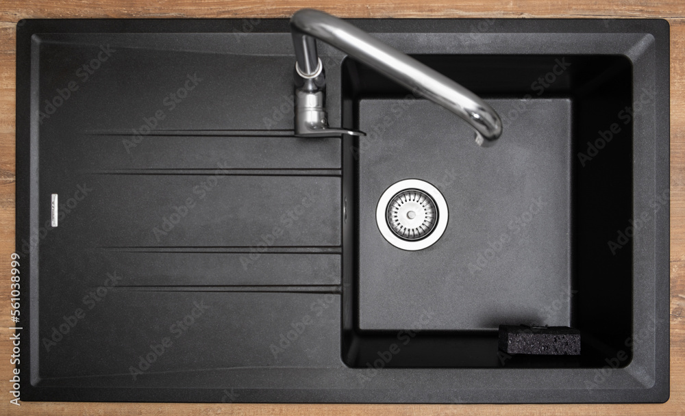 New clean granite kitchen sink black, strainer, holder for kitchen sponge. After. Drops water. House cleaning service. Top view New clean granite kitchen sink black, strainer, holder for kitchen sponge. After. Drops water. House cleaning service. Top view