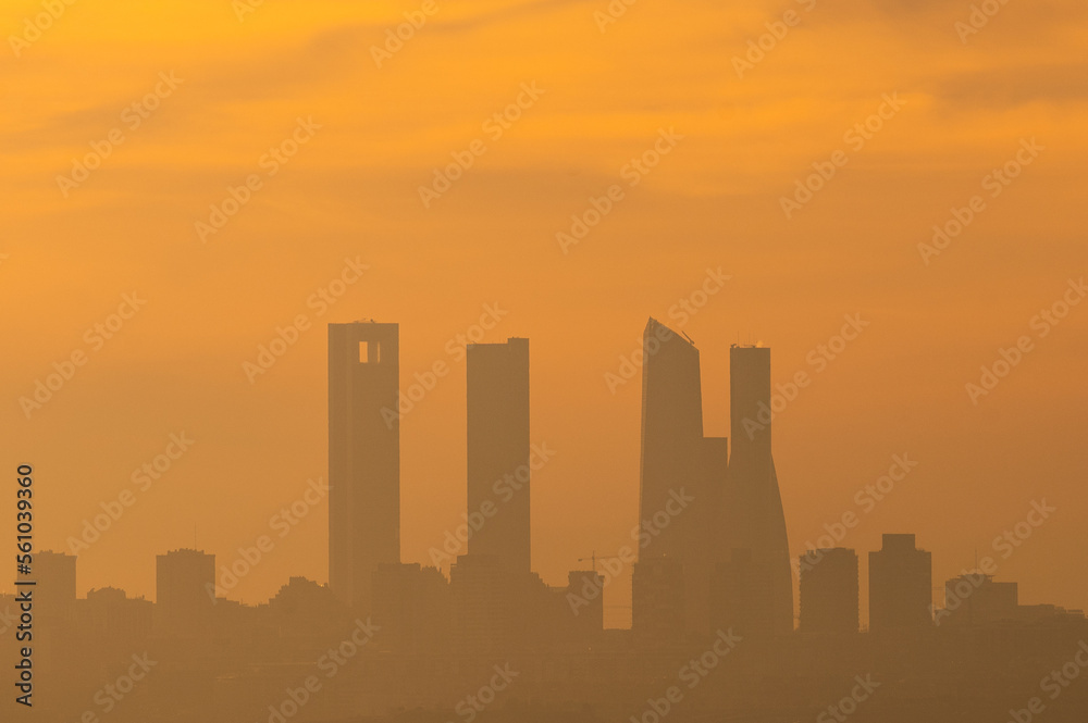 The sun silhouettes the skyscrapers of Madrid known as the 'Four Towers Business Area' during a day with pollution