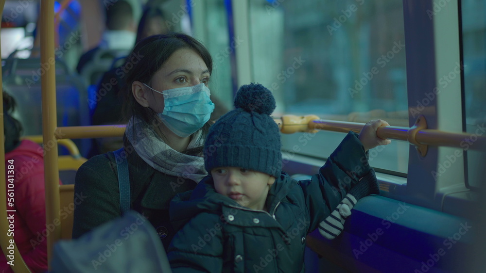 Mother and baby toddler riding bus wearing surgical face mask