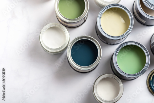 Fototapeta Naklejka Na Ścianę i Meble -  Tiny sample paint cans during house renovation, process of choosing paint for the walls, different green and beige colors, color charts on background