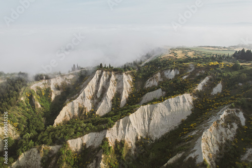 Karst landscape in Tuscany near Chiusure photographed with a drone. Fields, valley of Toscana, Siena region in Italy with little road and morning fog, mist. Small village of Chiusure.