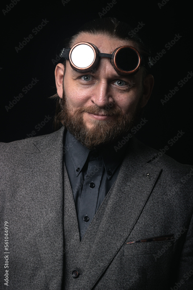 Obraz premium charismatic man in a classic suit and steampunk goggles on a black background stylish Portrait