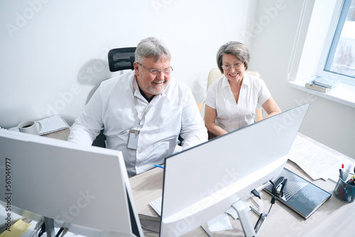 Doctor and elderly patient sitting in front of monitors in the diagnostic room