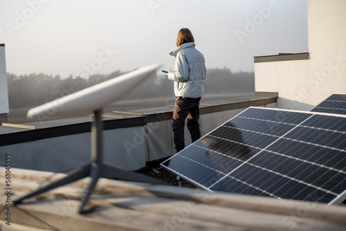 Woman uses satellite Internet on the roof of her house equipped with solar panels and satellite dish. Concept of new technologies