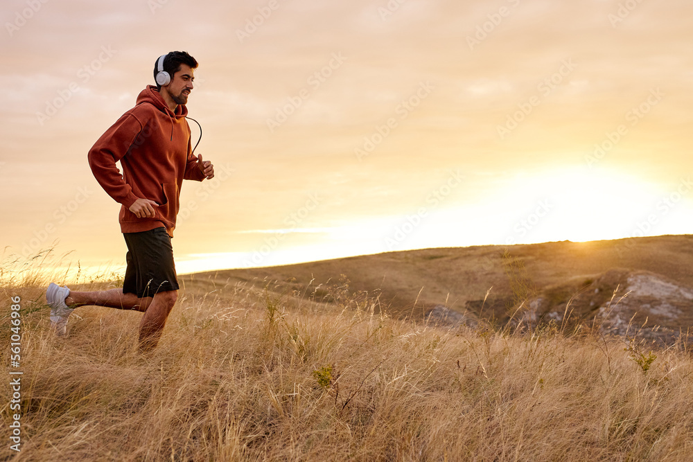 Running fitness man sprinting outdoors in beautiful landscape. Fit male runner training for marathon. Caucasian sport model in sportive clothes outfit. In Field in the morning, alone, listen to music Running fitness man sprinting outdoors in beautiful landscape. Fit male runner training for marathon. Caucasian sport model in sportive clothes outfit. In Field in the morning, alone, listen to music