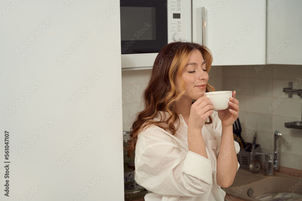 Smiling happy female is inhaling aroma of her favorite drink Smiling happy female is inhaling aroma of her favorite drink