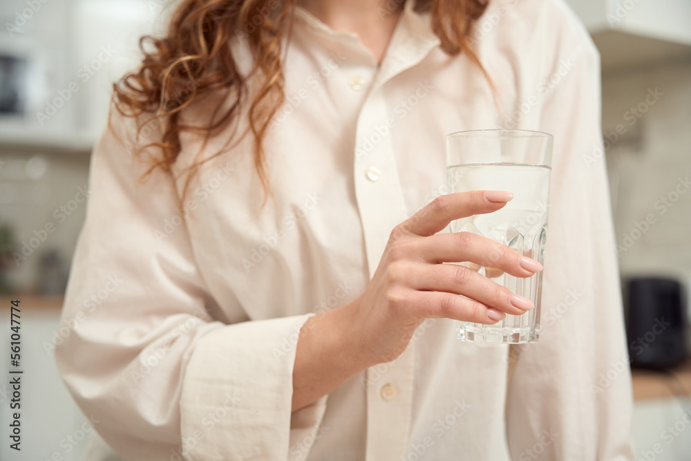 Female person drinking transparent liquid in kitchen Female person drinking transparent liquid in kitchen