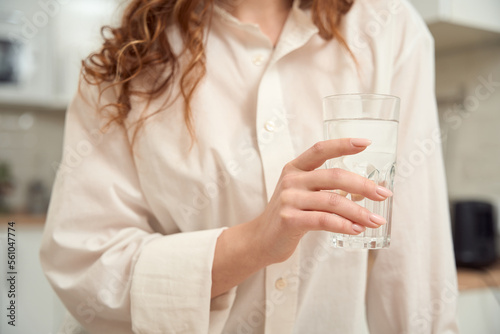 Female person drinking transparent liquid in kitchen