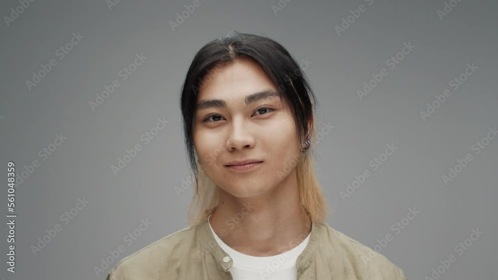 Young Adult Korean Man Looking at Camera Smiling Close-up. Portrait of Japanese Boy Isolated Alone on Grey Background. Asian 20s Person with Beautiful Eyes Turning Head and Happy in Colour Studio Shot Young Adult Korean Man Looking at Camera Smiling Close-up. Portrait of Japanese Boy Isolated Alone on Grey Background. Asian 20s Person with Beautiful Eyes Turning Head and Happy in Colour Studio Shot