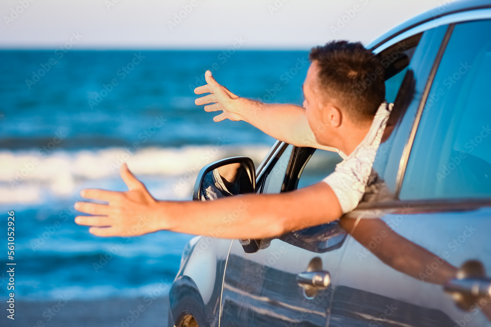 A Happy guy in the car by the sea in nature on vacation travel