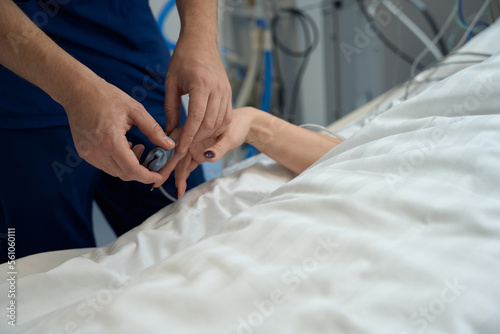 Lady lying in intensive care, nurse measuring pulse