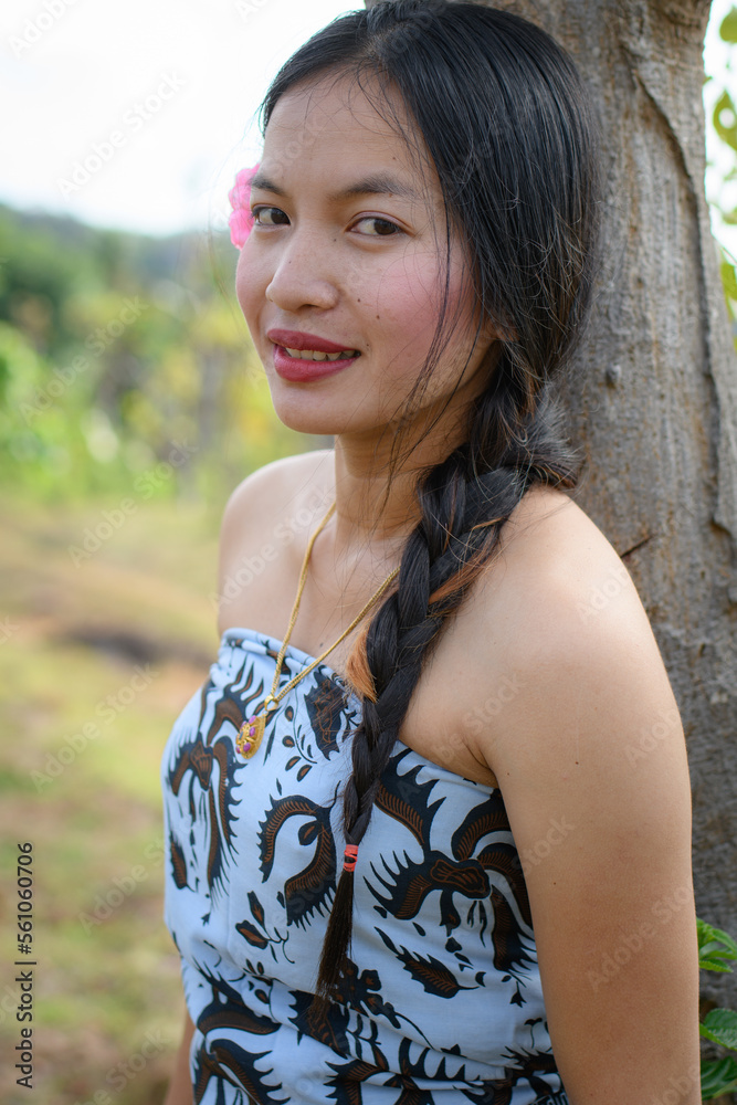 Close up Portrait girl with long hair and a flower behind her ear in classic shoulder loose-fit clothes with ponytails Close up Portrait girl with long hair and a flower behind her ear in classic shoulder loose-fit clothes with ponytails