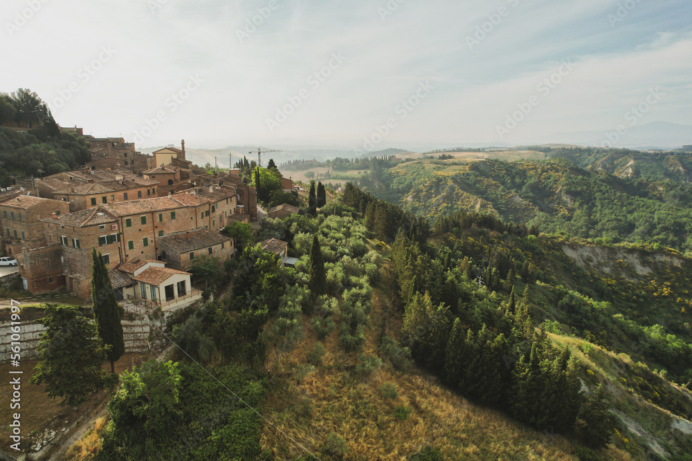 Small village of Chiusure on top of the hill surrounded by Karst cliffs landscape photographed with a drone. Toscana, Tuscany, Asciano, province of Siena in Italy with a little mud road 06.16.2021