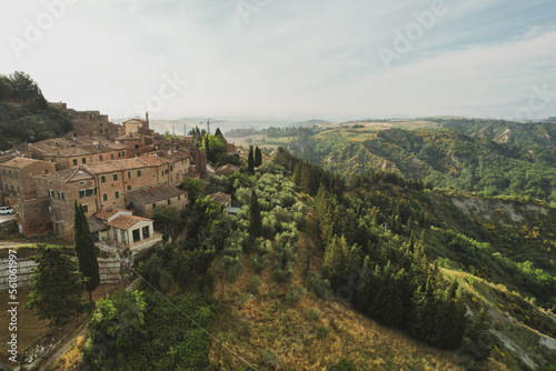Small village of Chiusure on top of the hill surrounded by Karst cliffs landscape photographed with a drone. Toscana, Tuscany, Asciano, province of Siena in Italy with a little mud road 06.16.2021