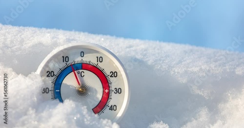 Thermometer with celsius scale in snow demonstrates ambient temperature rising up from minus 9 degrees to minus 4 - winter weather change concept 4K timelapse photo