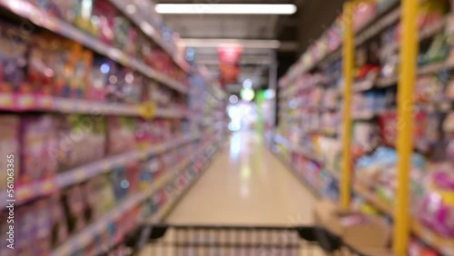 Wallpaper Mural Blurred and trolley shopping cart moving through food product shelves interior defocused background in the supermarket. person pushing a shopping cart in a supermarket store in slow motion shot. Torontodigital.ca