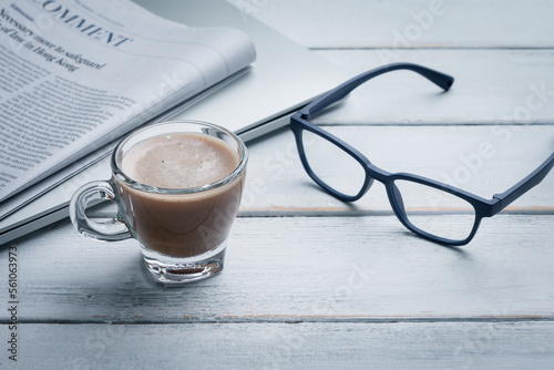 Black cup of coffee, notebook, newspaper and laptop on the table, morning news. get ready for work in the morning