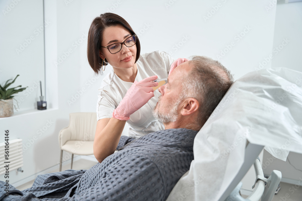 Obraz premium Doctor uses modern fillers for rejuvenating course for adult patient