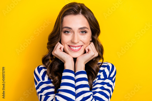 Photo portrait of attractive young woman fists touch face adorable admire dressed stylish striped look isolated on yellow color background