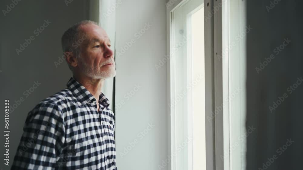 An old man in a hospice at the window. Farewell to relatives. Separation concept An old man in a hospice at the window. Farewell to relatives. Separation concept